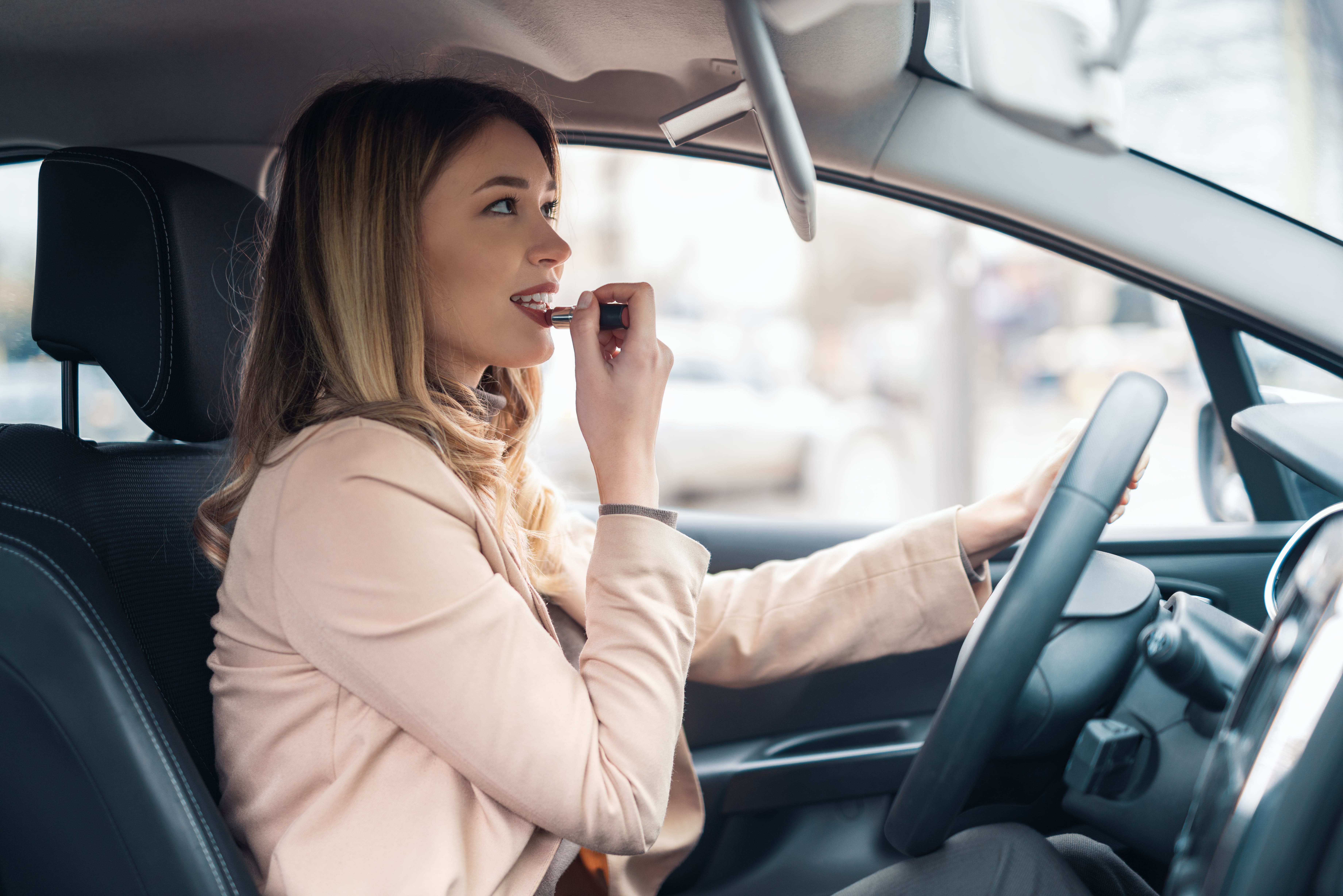Woman applying lipstick in a car